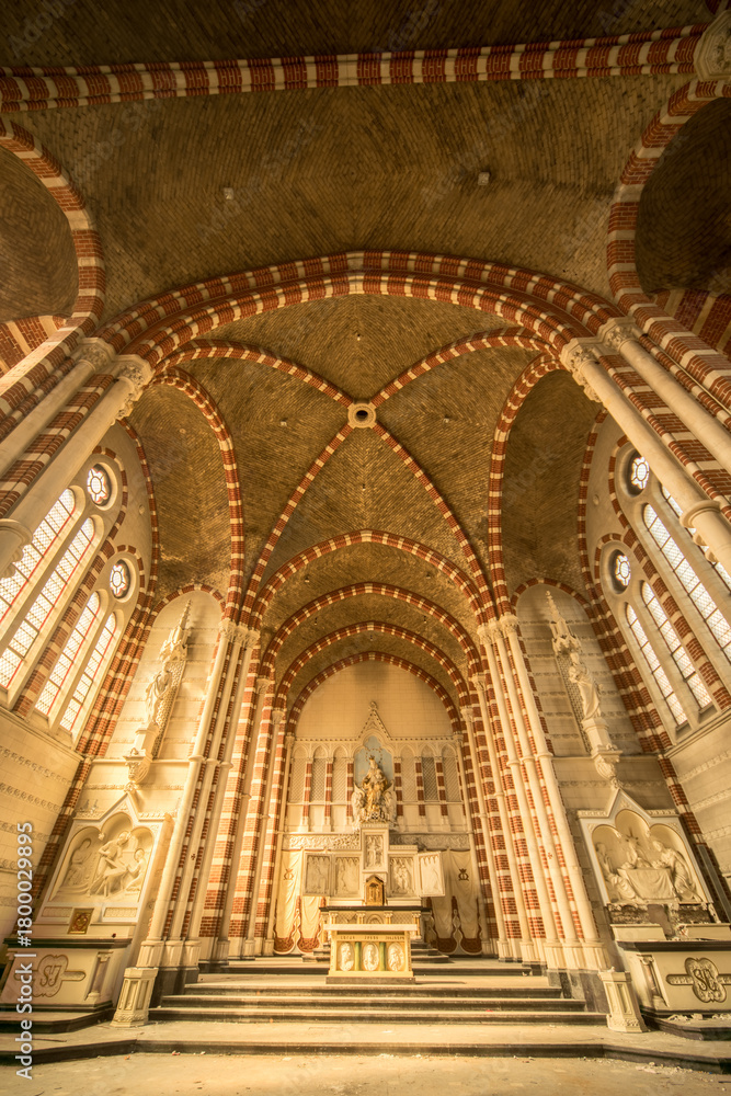 Fototapeta premium Sunlit Abandoned Monastery Interior with Striped Brick Vaults and Ornate Altar