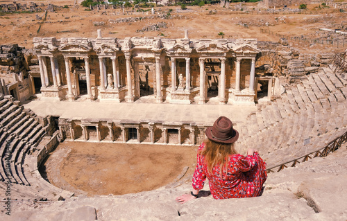 A tourist in a beautiful red dress at the historical monument of the theater of the ancient city of Hierapolis