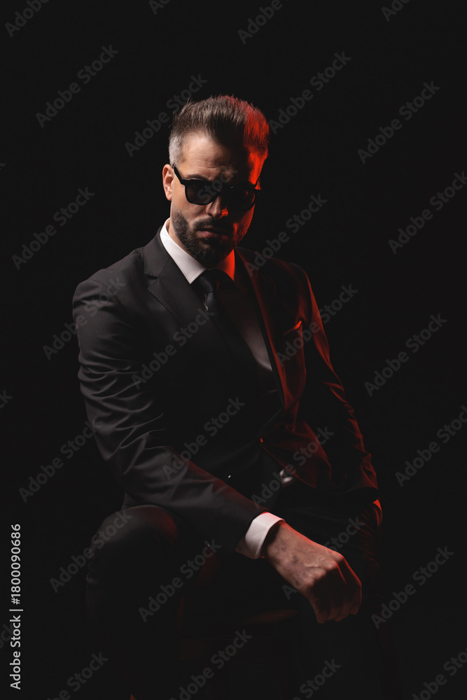 Obraz premium Serious man in sunglasses posing on chair