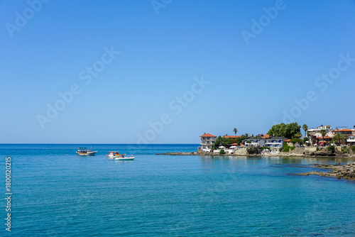 Fototapeta Naklejka Na Ścianę i Meble -  A calm blue sea with a few boats floating on it Side Antik Liman