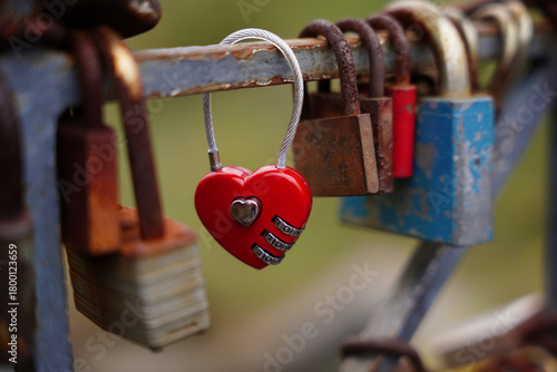 Red heart-shaped love lock hanging on a metal railing, a romantic symbol of affection and
commitment placed on a city bridge.