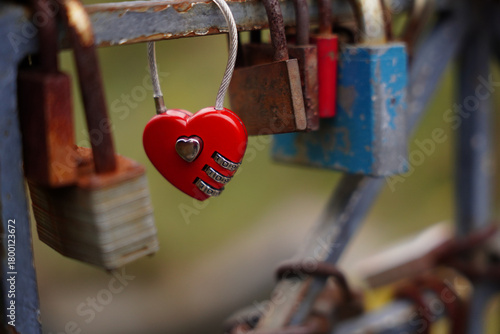 Red heart-shaped love lock hanging on a metal railing, a romantic symbol of affection and
commitment placed on a city bridge.