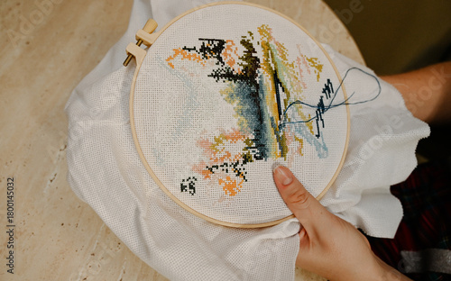 The process of hand embroidery with a cross on a white canvas