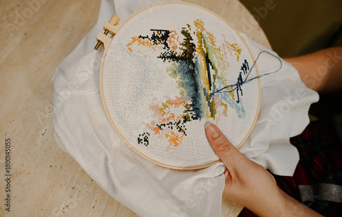 The process of hand embroidery with a cross on a white canvas