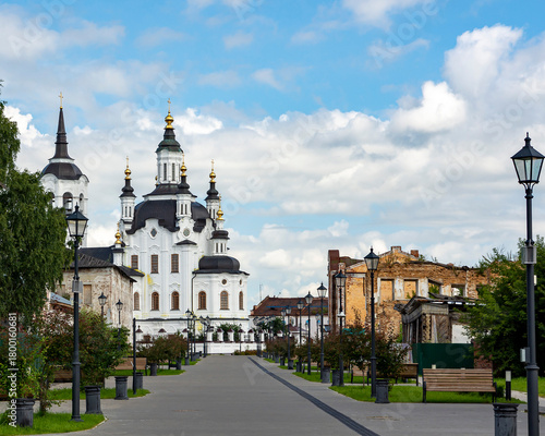 Fototapeta Naklejka Na Ścianę i Meble -  A street in a recreation park in a small Siberian town, bathed in autumn sunshine. At the end of the street is a church. Tourism in Russia