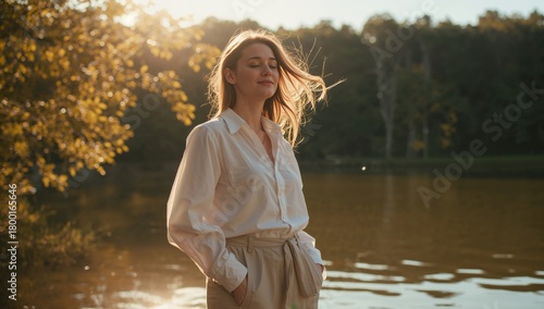 Woman Enjoying a Peaceful Moment by the Serene Lake in the Warm Evening Sunlight