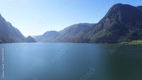 Drone rising from the ground and revealing the fjord in Odda, showing Sandvinvatnet with steep mountains, deep blue water, and dramatic Norwegian scenery.