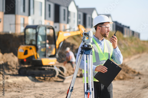 Slika na platnu Surveyor communicating on construction site with theodolite