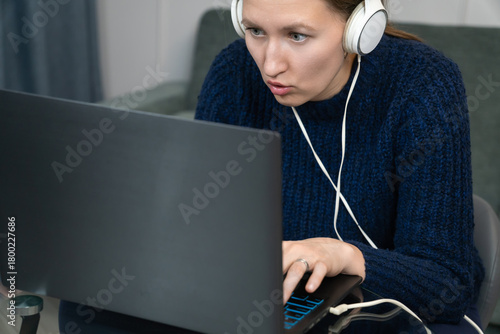 Papier peint Office worker wearing headphones frowning while looking at laptop screen, experi
