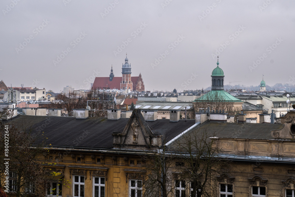 Naklejka premium Krakow cityscape featuring historic buildings and domes under a cloudy sky.