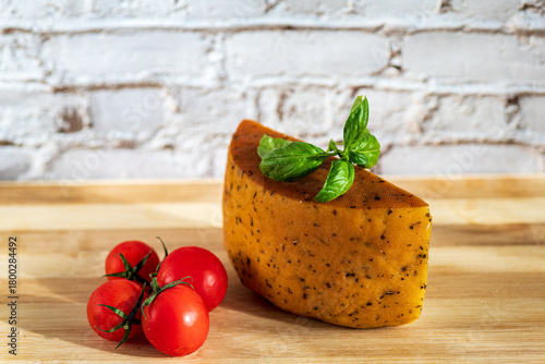 Slices of semi-hard cheese arranged neatly with fresh basil leaves on top. The combination of creamy-yellow cheese and vibrant green basil creates a clean, appetizing visual contrast.