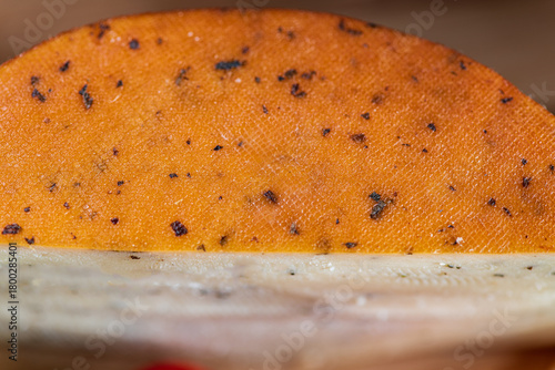 Slices of semi-hard cheese arranged neatly with fresh basil leaves on top. The combination of creamy-yellow cheese and vibrant green basil creates a clean, appetizing visual contrast.