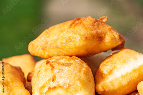 Golden, freshly fried fritters arranged on a plate, featuring a crispy exterior and a soft, airy inside. Warm lighting enhances their rich golden color and homemade rustic appearance. 