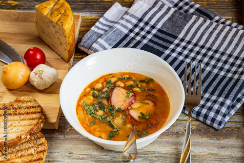 A hearty bowl of cooked bean stew with tender pieces of meat, served in a clean white dish. The warm, rich broth highlights the soft beans and juicy meat, while natural lighting 