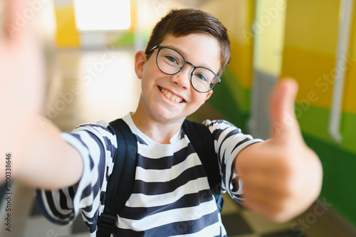 Smiling student taking selfie and giving thumbs up at school