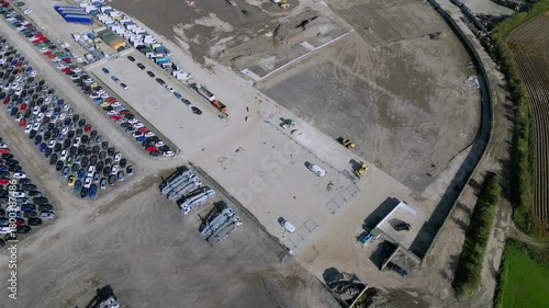 Cars parked in large lot next to construction site with machinery and workers busy at work at Copart yard, York, North Yorkshire.