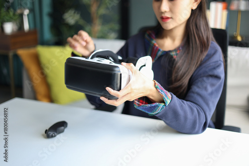 Young asian woman wearing virtual reality glasses in living room at home.