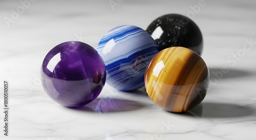 A collection of colorful polished gemstone spheres including amethyst, tiger's eye, and agate on a marble surface.