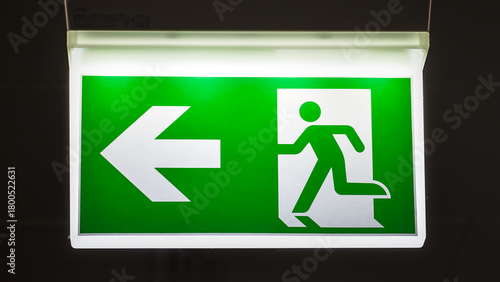 Illuminated emergency exit sign at night, glowing clearly in the darkness as a safety indicator.