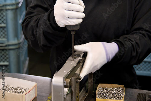 工場で部品のねじを締める職人の手