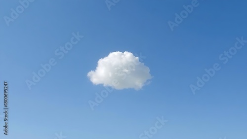 Single fluffy cloud in a vast blue sky, serene atmosphere.