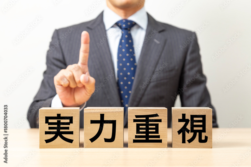 Obraz premium 「実力重視」と書かれたブロックとビジネスマン