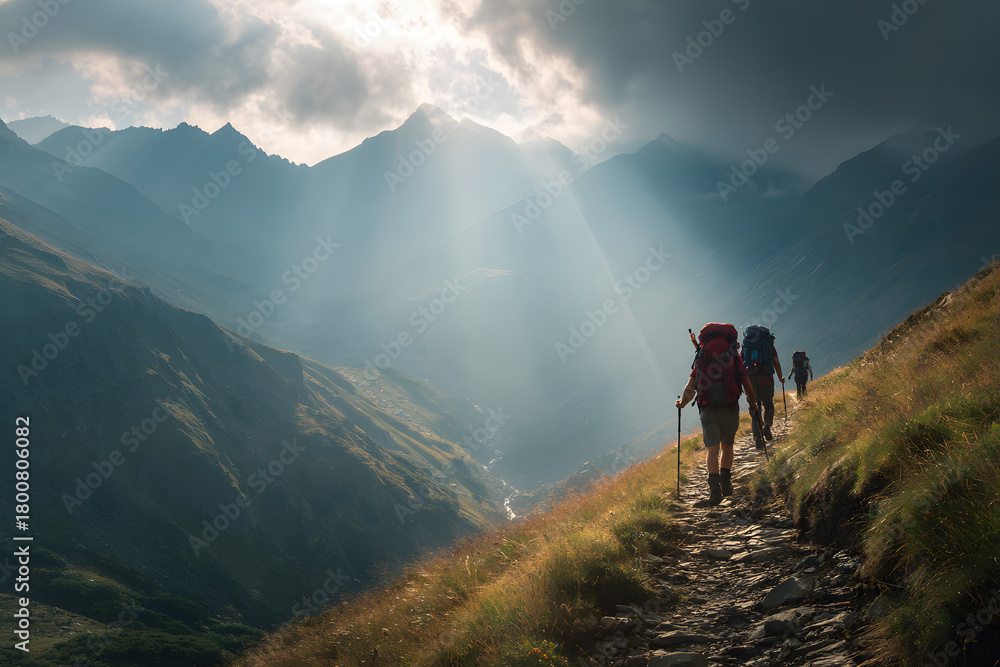 Fototapeta premium Hikers trek along a mountainous trail at sunset with backpacks and canes in a stunning landscape