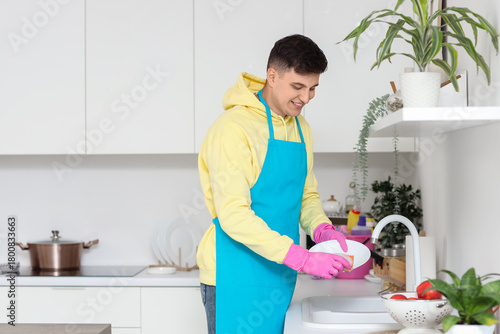 Young man washing dishes in...