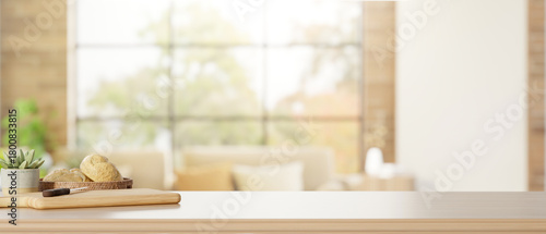 Fototapeta Naklejka Na Ścianę i Meble -  Bread and knife on cutting board with pot plant on wooden counter table across window in living room