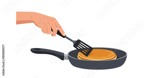 A human hand using a spatula to flip a freshly cooked golden pancake in a non-stick frying pan. An illustration representing the process of making breakfast