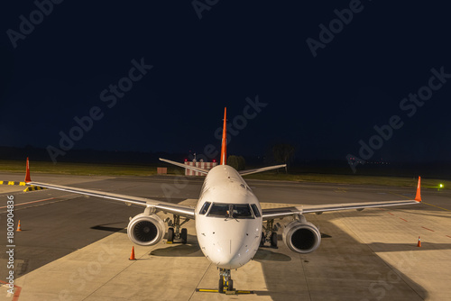 A passenger plane is parked at the night airport