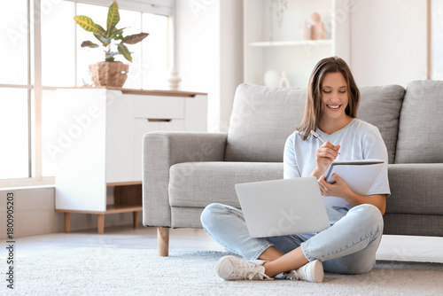 Young woman with notebook and laptop sitting at home