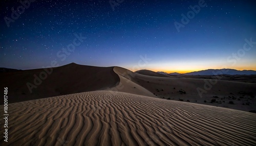 Fototapeta Naklejka Na Ścianę i Meble -  A serene desert scene under a starlit night sky, with undulating sand dunes in the foreground and mountains in distance