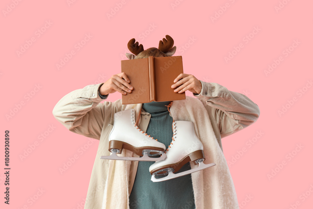 Naklejka premium Young man with book and ice skates on pink background. Christmas celebration