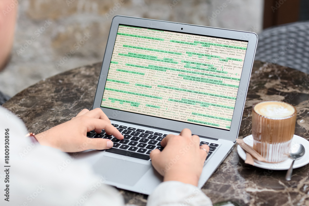 Fototapeta premium Male programmer working with laptop at table in street cafe, closeup