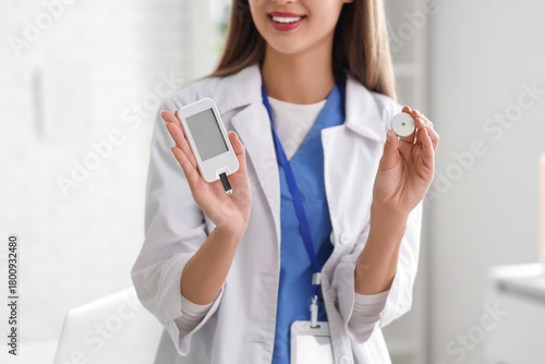 Female doctor with glucometer and glucose sensor in clinic, closeup