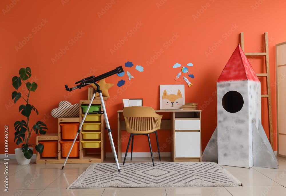 Fototapeta premium Interior of stylish children's room with cardboard rocket, table, toys and modern telescope