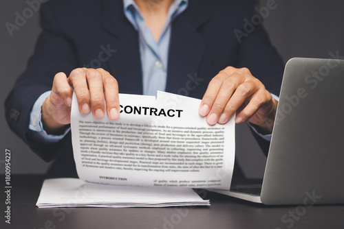 Hand tearing legal contract to end agreement.