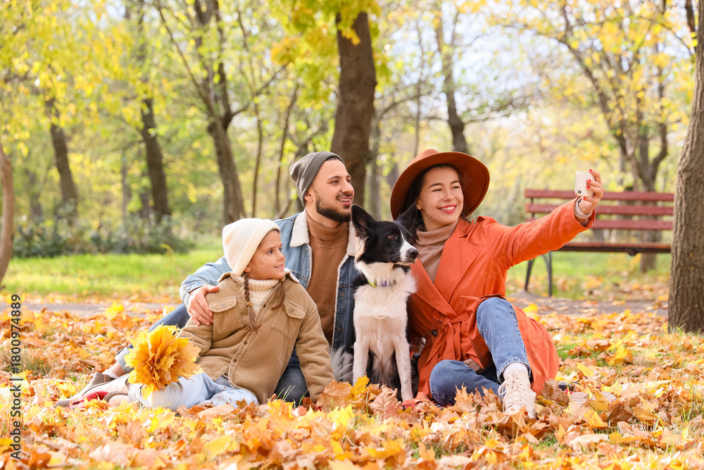 Fototapeta premium Happy family with dog taking selfie in autumn park