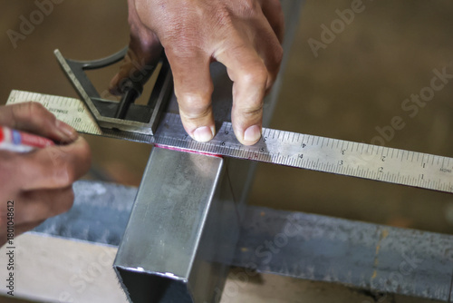 Φωτογραφία Focused worker hand using ruler and tool for accurate measuring and marking metal beam during construction in workshop