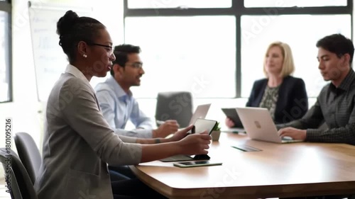 Wallpaper Mural A diverse group collaborates around a wooden table in a bright office setting. They are working with laptops and tablets, focusing on a business meeting and planning. Torontodigital.ca