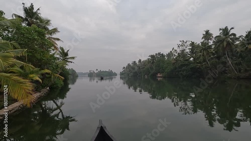 A peaceful early morning boat ride through the serene canals of Alappuzha near Varkala, Kerala - India. The footage features an old traditional wooden boat gliding gently along the calm backwaters.