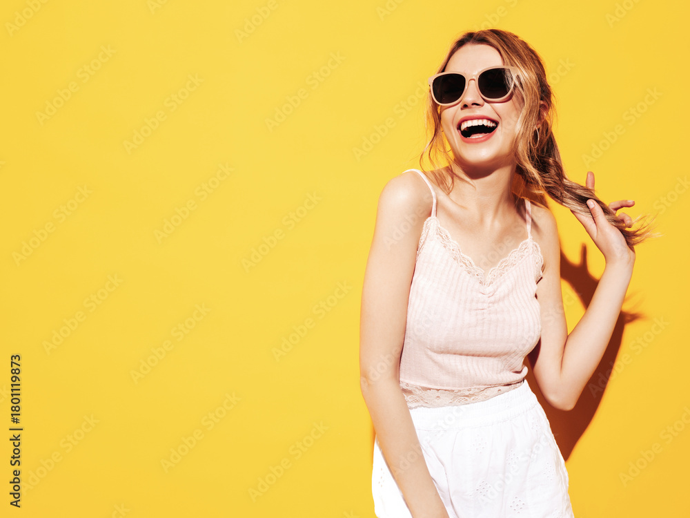 Fototapeta premium Young beautiful smiling female in trendy summer clothes. Sexy carefree woman posing near blue yellow in studio. Positive model having fun. Cheerful and happy. In sunglasses. Screaming and shouting