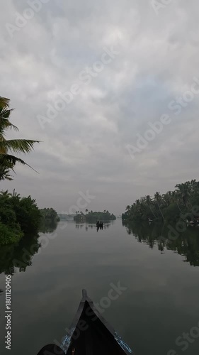 A peaceful early morning boat ride through the serene canals of Alappuzha near Varkala, Kerala, India. The footage features an old traditional wooden boat gliding gently along the calm backwaters.