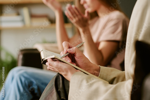 Bild auf Leinwand Middle aged Caucasian woman holding notebook and pen listening attentively while