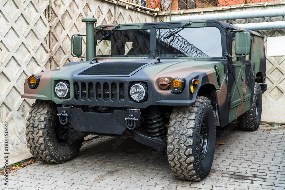 Fototapeta premium Military Humvee parked on an street, showcasing its rugged design and operational readiness in a secure military base. Khaki camouflage military Hummer front view. Army USA. 