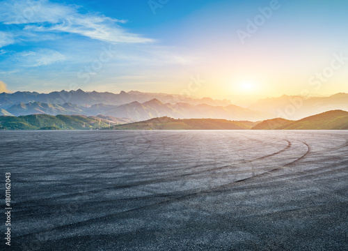 Empty race track ground with tire track and beautiful mountain range natural landscape at sunset