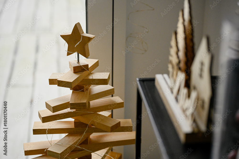 Fototapeta premium Détail d'un sapin de Noël fabriqué en plaque de bois, placé devant une fenêtre, pour décorer un intérieur pour les fêtes de fin d'année
