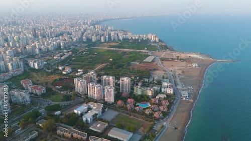 Mersin, Turkey. Aerial drone view of Mediterranean coastline at sunset. Sandy beach, sea waves, and residential district with apartment blocks in golden evening light.. Aerial View