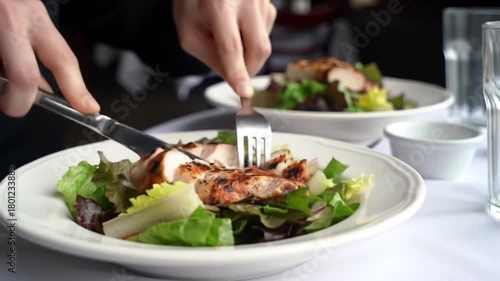 Wallpaper Mural Close-up of a person cutting grilled chicken on a fresh salad at a restaurant setting Torontodigital.ca